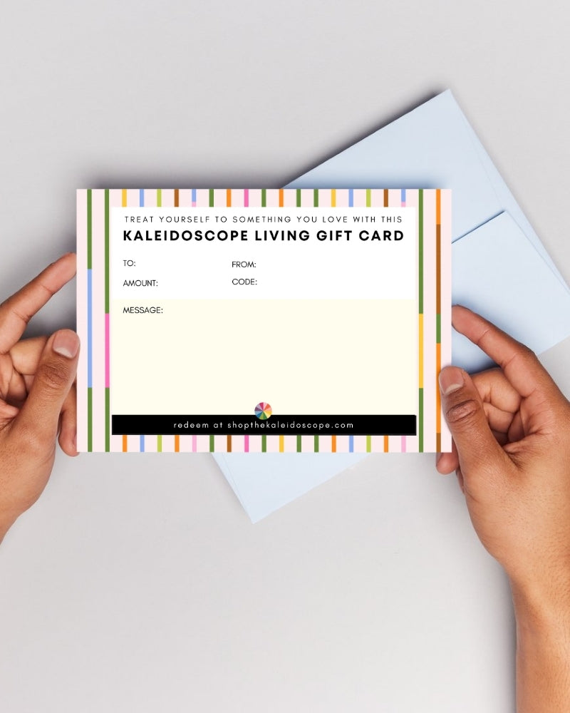 woman's hands holding a Kaleidoscope Living Gift Card with an open blue envelope in the background