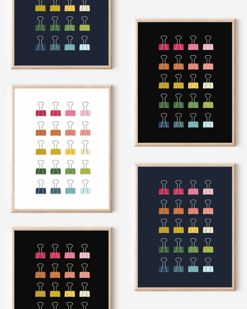Framed art prints featuring minimalist illustrations of Binder Clips in rainbow hues on black, navy blue and white backgrounds.