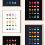 Framed art prints featuring minimalist illustrations of Binder Clips in rainbow hues on black, navy blue and white backgrounds.