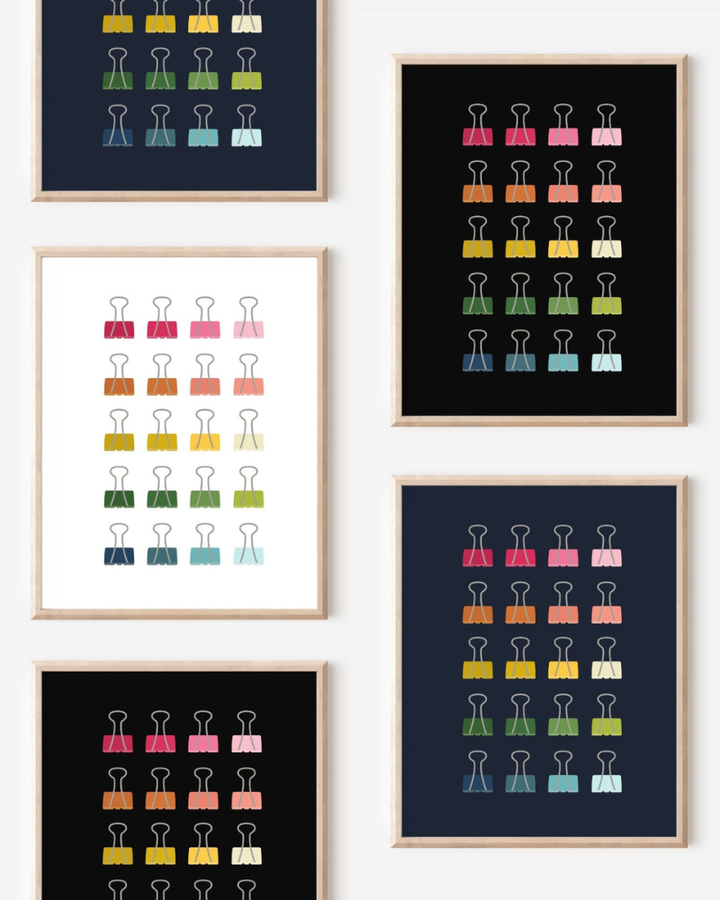 Framed art prints featuring minimalist illustrations of Binder Clips in rainbow hues on black, navy blue and white backgrounds.