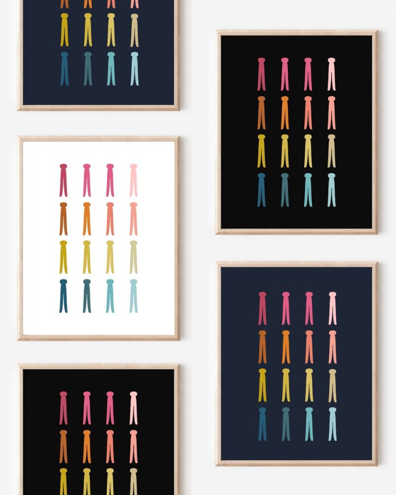 Framed art prints featuring minimalist illustrations of Clothespins in rainbow hues on black, navy blue and white backgrounds.
