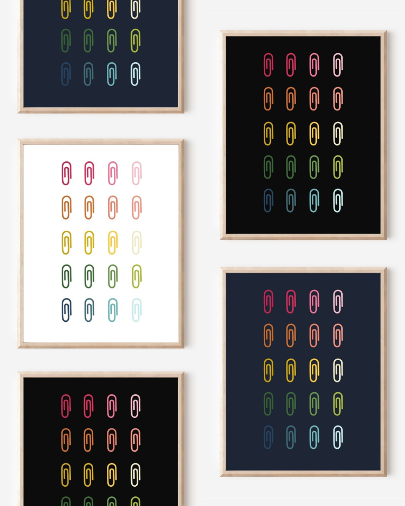 Framed art prints featuring minimalist illustrations of Paper Clips in rainbow hues on black, navy blue and white backgrounds.