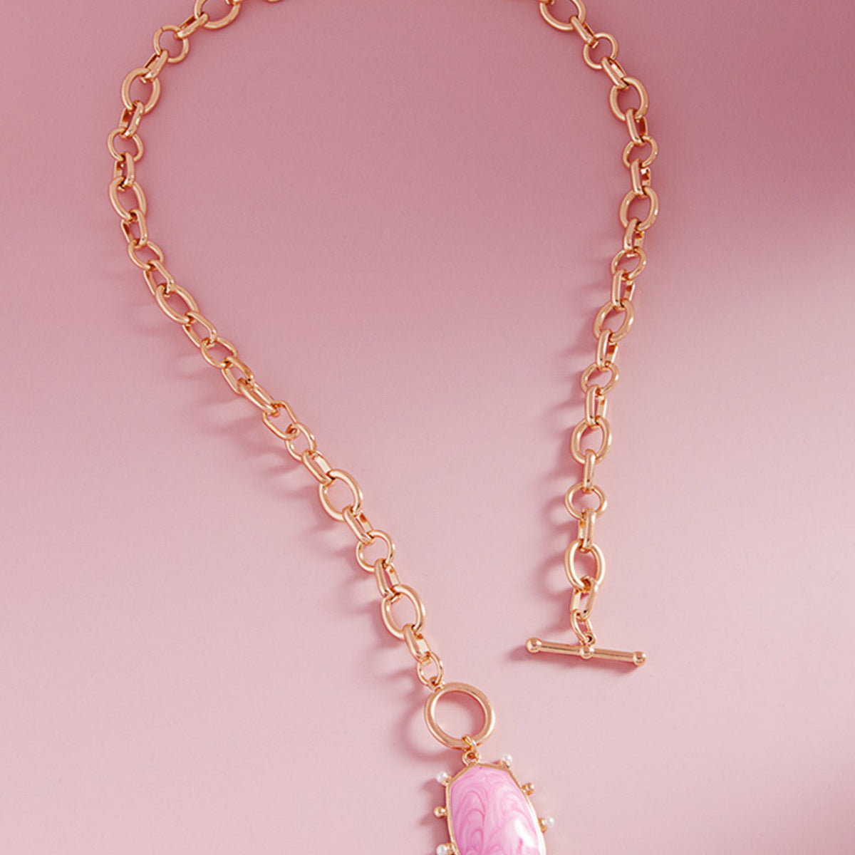 A pink marbled enamel oval pendant on a gold chain with a toggle closure by Kaleidoscope Living.