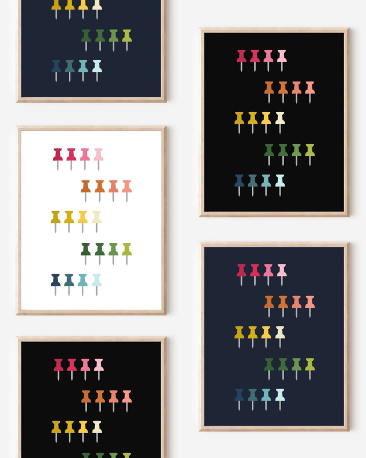 Framed art prints featuring minimalist illustrations of Push Pins in rainbow hues on black, navy blue and white backgrounds.