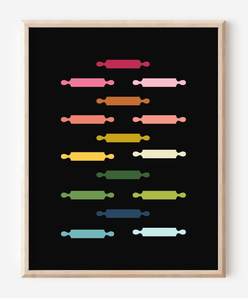 Kitchen wall art featuring rolling pins in ombre rainbow hues arranged in a grid pattern on a black background.