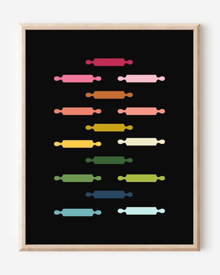 Kitchen wall art featuring rolling pins in ombre rainbow hues arranged in a grid pattern on a black background.