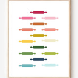 Kitchen wall art featuring rolling pins in ombre rainbow hues arranged in a grid pattern on a white background.
