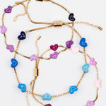 Three gold chain bracelets with pink, blue and purple enamel hearts from Kaleidoscope Living.