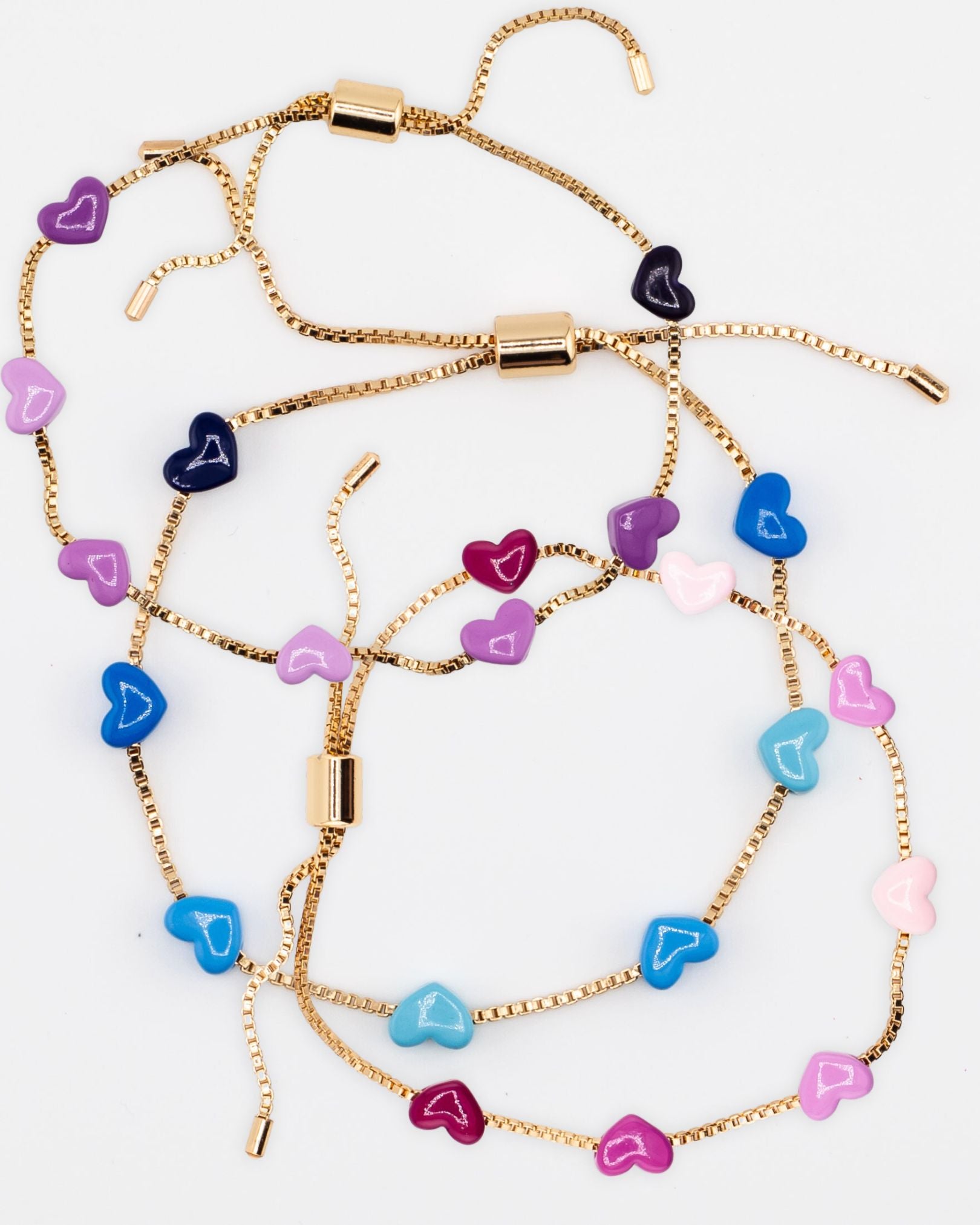 Three gold chain bracelets with pink, blue and purple enamel hearts from Kaleidoscope Living.