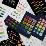 stack of rainbow graphic art prints featuring everyday objects like laundry baskets, toilet plungers, toothbrushes and scissors laid on a light gray surface