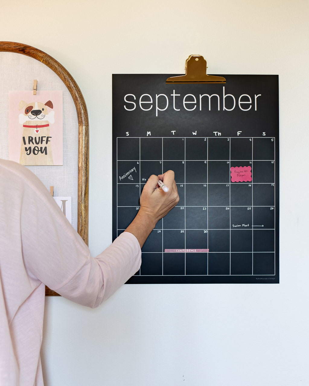 Woman writing on erasable black wall calendar with white chalk marker