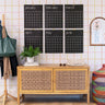 Large reusable black calendar on a wall with a wooden cabinet below and colorful decor items around.