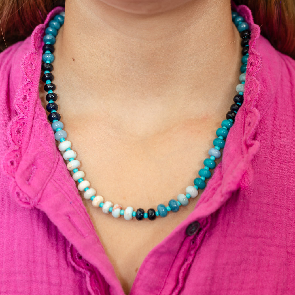 Girl wearing a natural stone beaded necklace in shades of blues and whites with alternating smaller turquoise beads.