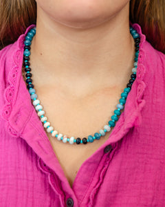 Girl wearing a natural stone beaded necklace in shades of blues and whites with alternating smaller turquoise beads.