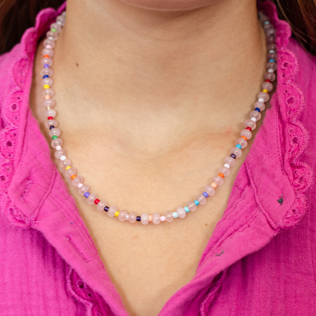 Colorful beaded necklace with light pink beads along with rainbow bead accents.
