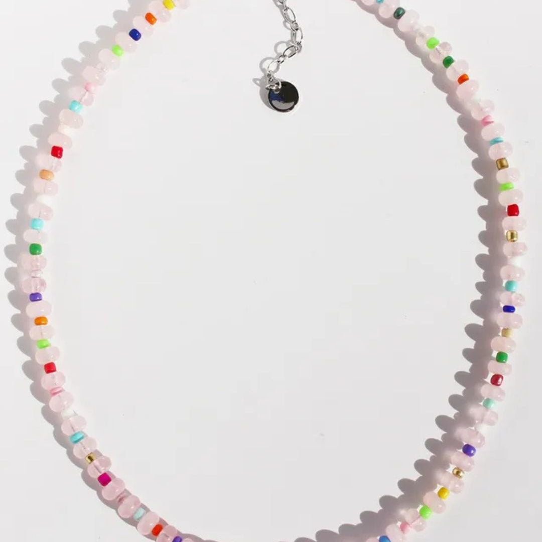 A blush pink natural stone necklace with multicolored tiny beads, featuring a silver clasp and extender.