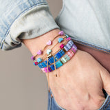 Hand wearing multiple colorful beaded bracelets with gold accents from Kaleidoscope Living