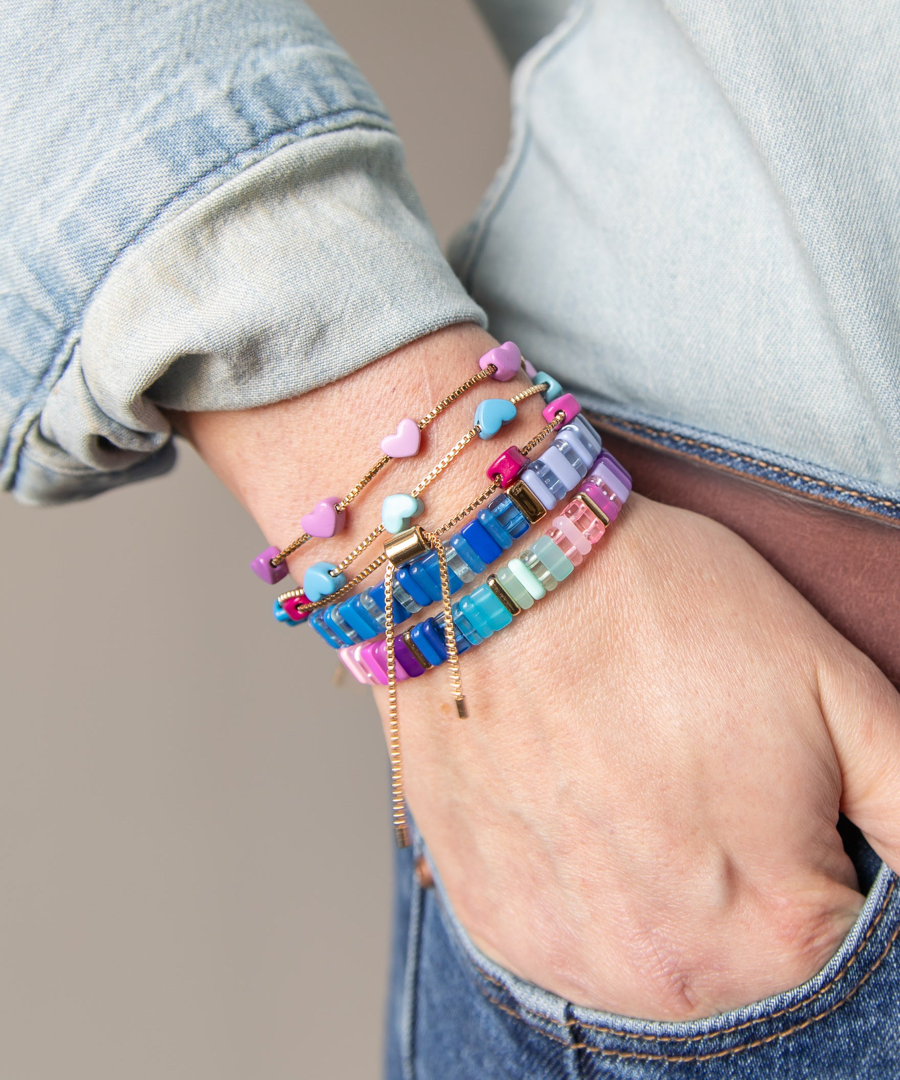Hand wearing multiple colorful beaded bracelets with gold accents from Kaleidoscope Living