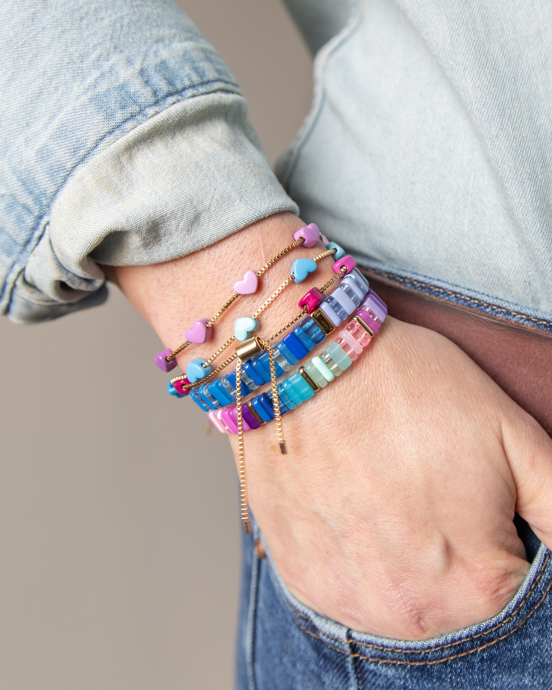 Hand wearing multiple colorful beaded bracelets with gold accents from Kaleidoscope Living