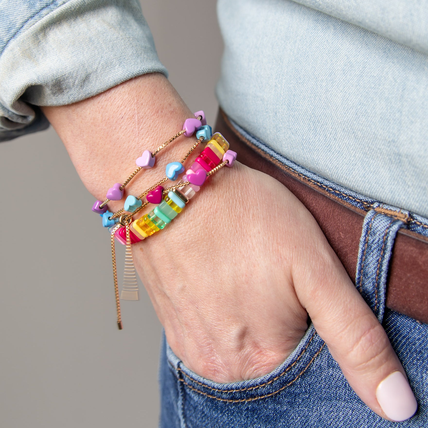 Stacked colorful bracelets with gold chain accents by Kaleidoscope Living.