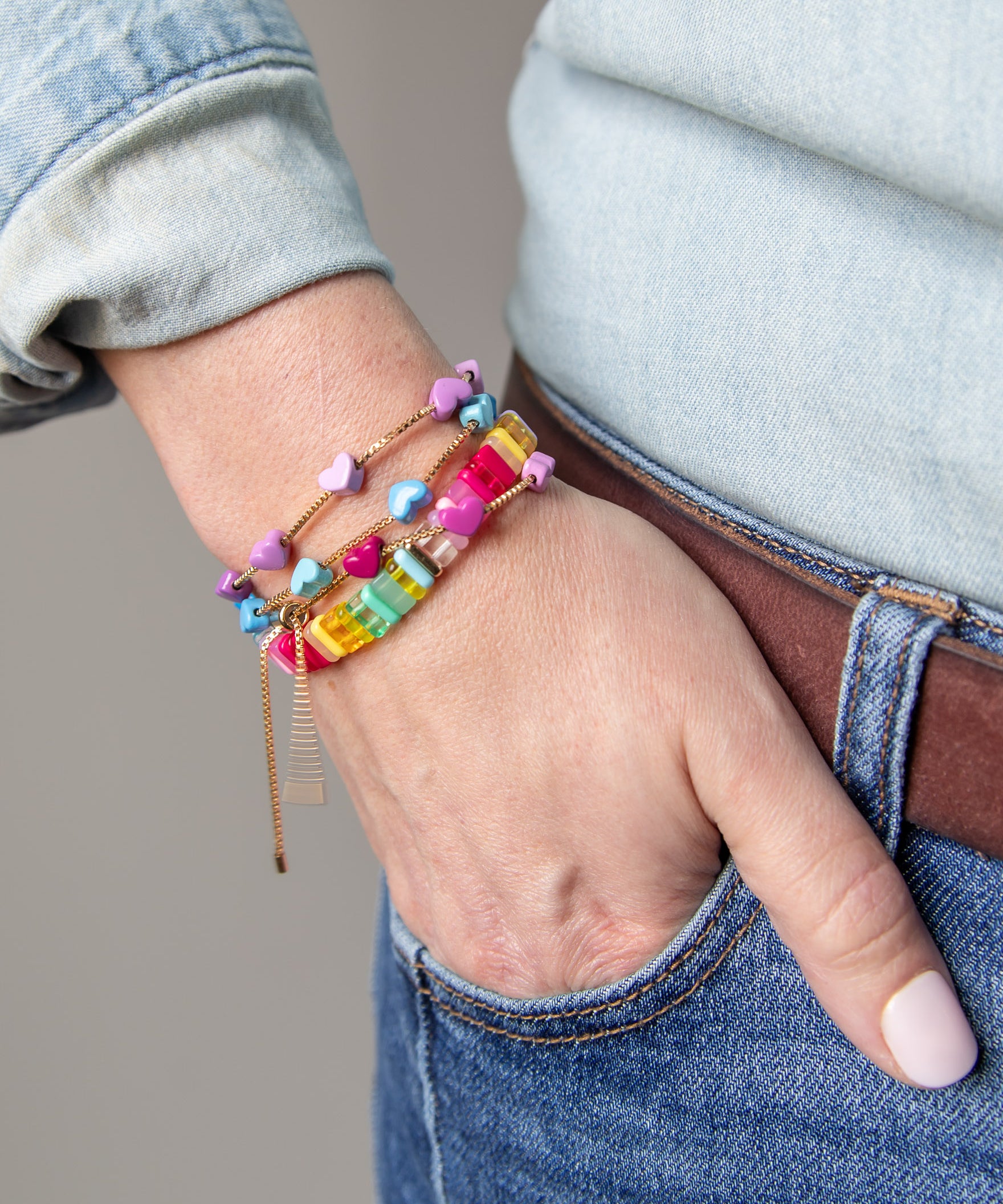 Stacked colorful bracelets with gold chain accents by Kaleidoscope Living.