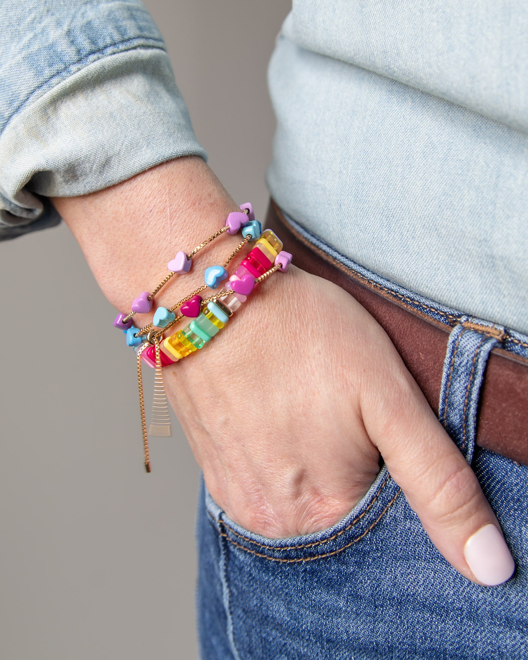 Stacked colorful bracelets with gold chain accents by Kaleidoscope Living.