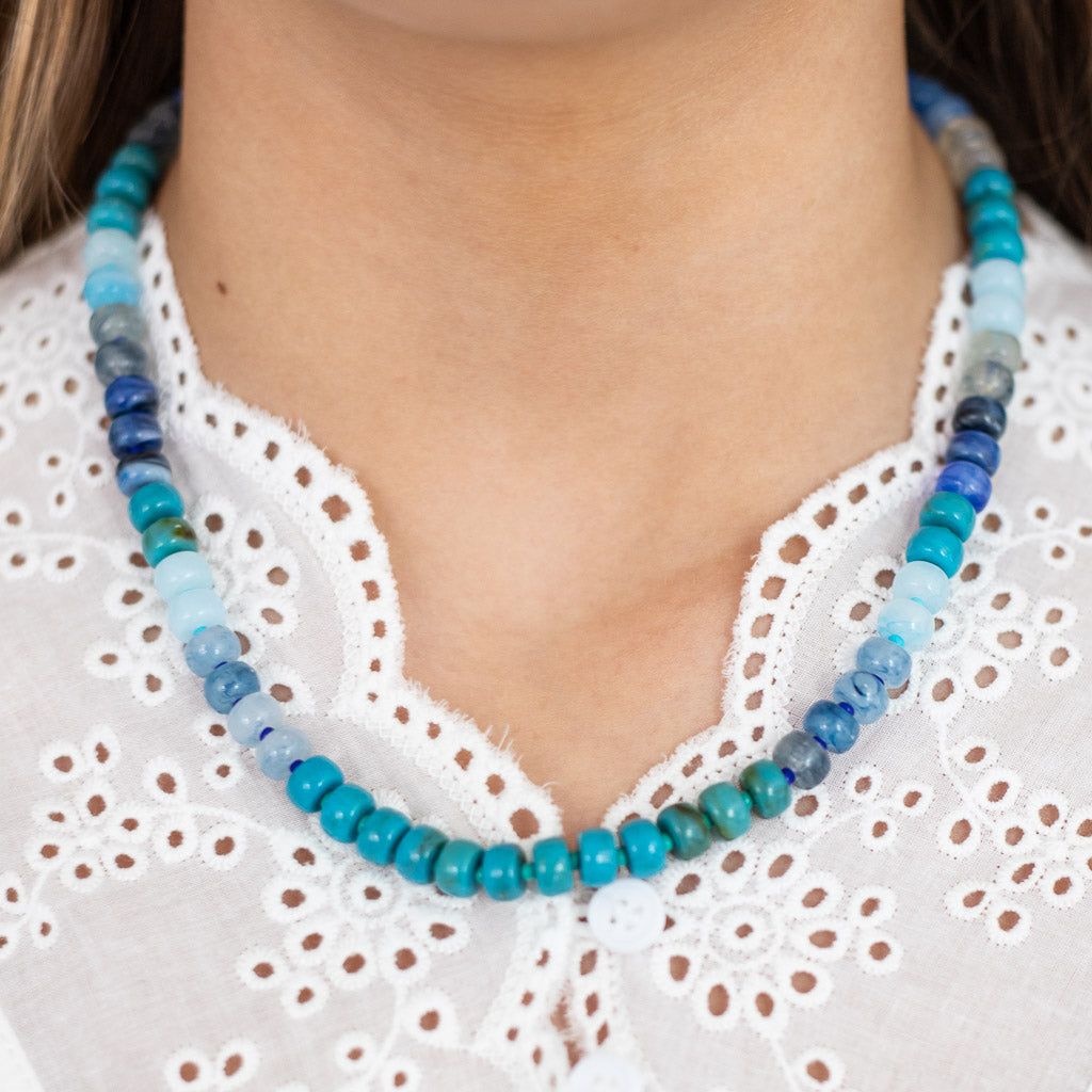 Close up of resin beaded necklace in shades on blue on girl in white top