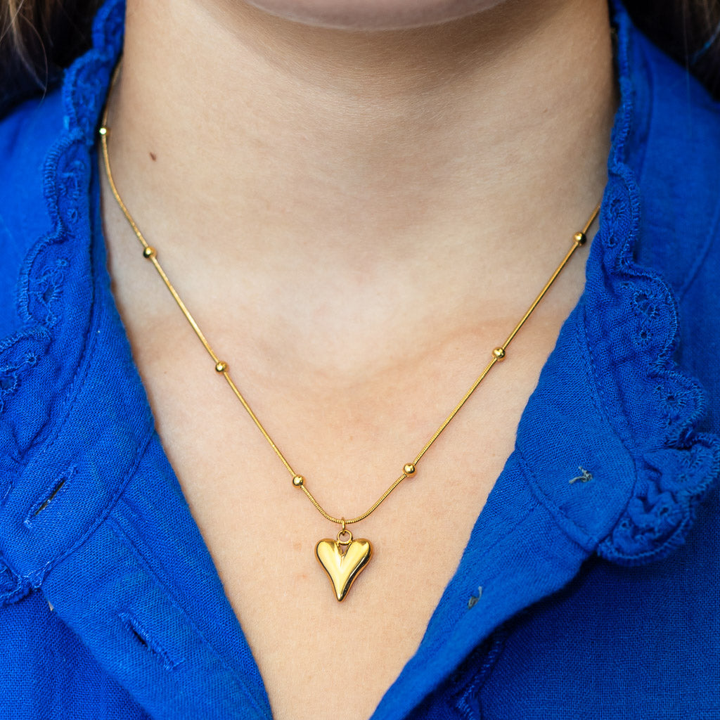 Close up of a gold necklace with a heart pendant from Kaleidoscope Living.