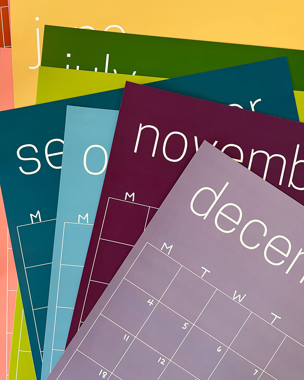 Stack of the reusable rainbow wall calendars from Kaleidoscope Living.