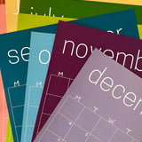 Stack of the reusable rainbow wall calendars from Kaleidoscope Living.