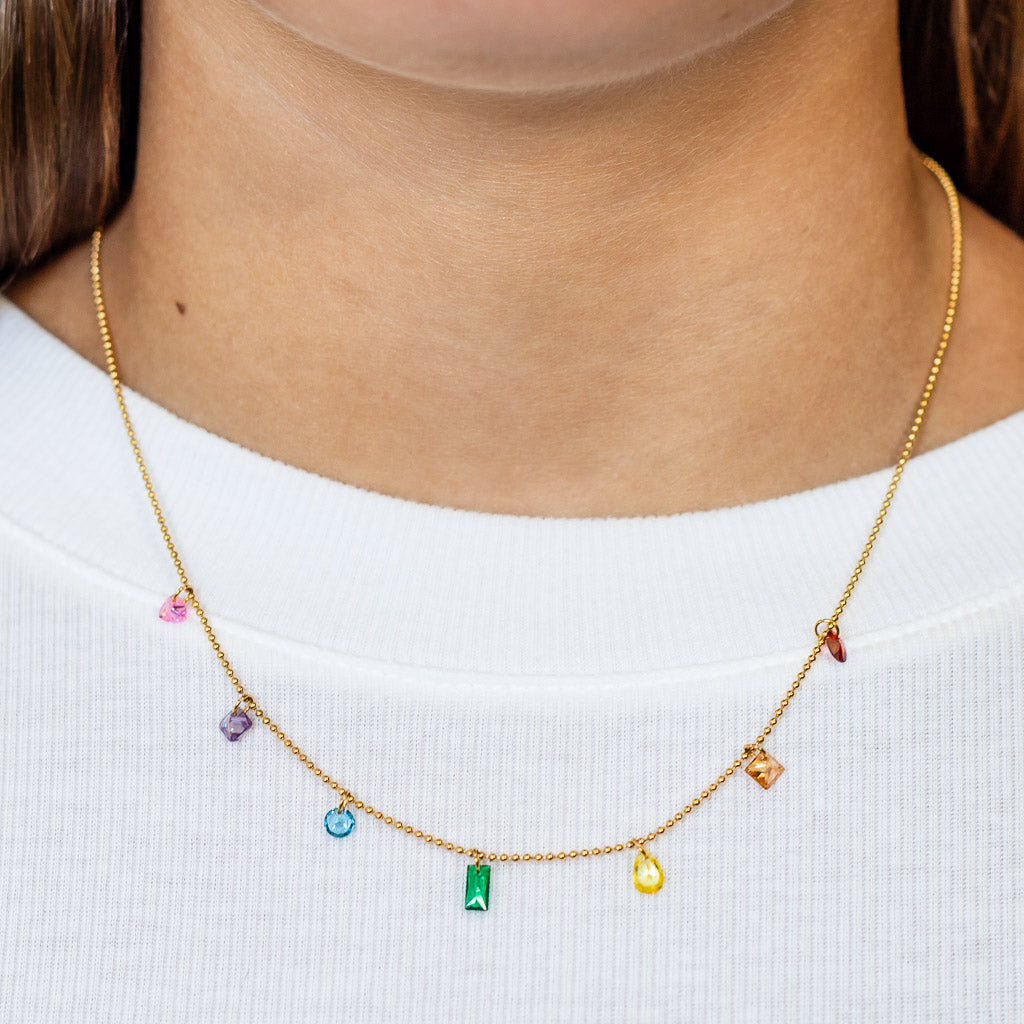 Necklace with colorful gemstones worn by a woman wearing a white t-shirt