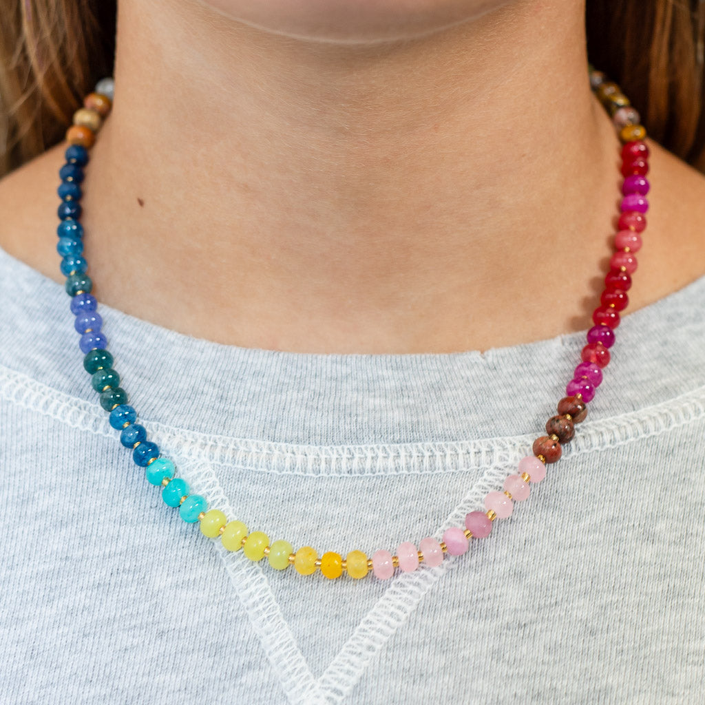 Multicolored natural stone beaded necklace strung in a rainbow palette with gold accents.
