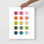 kitchen art print with a white background and grid of colorful clip art of coffee mugs in ombre rainbow colors ranging from pinks to blues