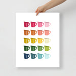 kitchen art print with a white background and grid of colorful clip art of measuring cups in ombre rainbow colors ranging from pinks to blues