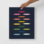 kitchen art print with a navy background and grid of colorful clip art of rolling pins in ombre rainbow colors ranging from pinks to blues