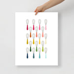 kitchen art print with a white background and grid of colorful clip art of whisks in ombre rainbow colors ranging from pinks to blues