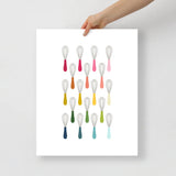 kitchen art print with a white background and grid of colorful clip art of whisks in ombre rainbow colors ranging from pinks to blues
