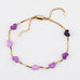 Gold adjustable bracelet with purple enamel hearts on a white background