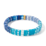 A blue-toned resin tile beaded stretch bracelet with soft lavenders, aquas, and deep navy accents.