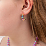 Close-up of a person wearing colorful hoop earring with green, blue, yellow and gold accents.  