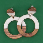 Wooden and white resin hoop earrings on a green background