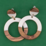 Wooden and white resin hoop earrings on a green background