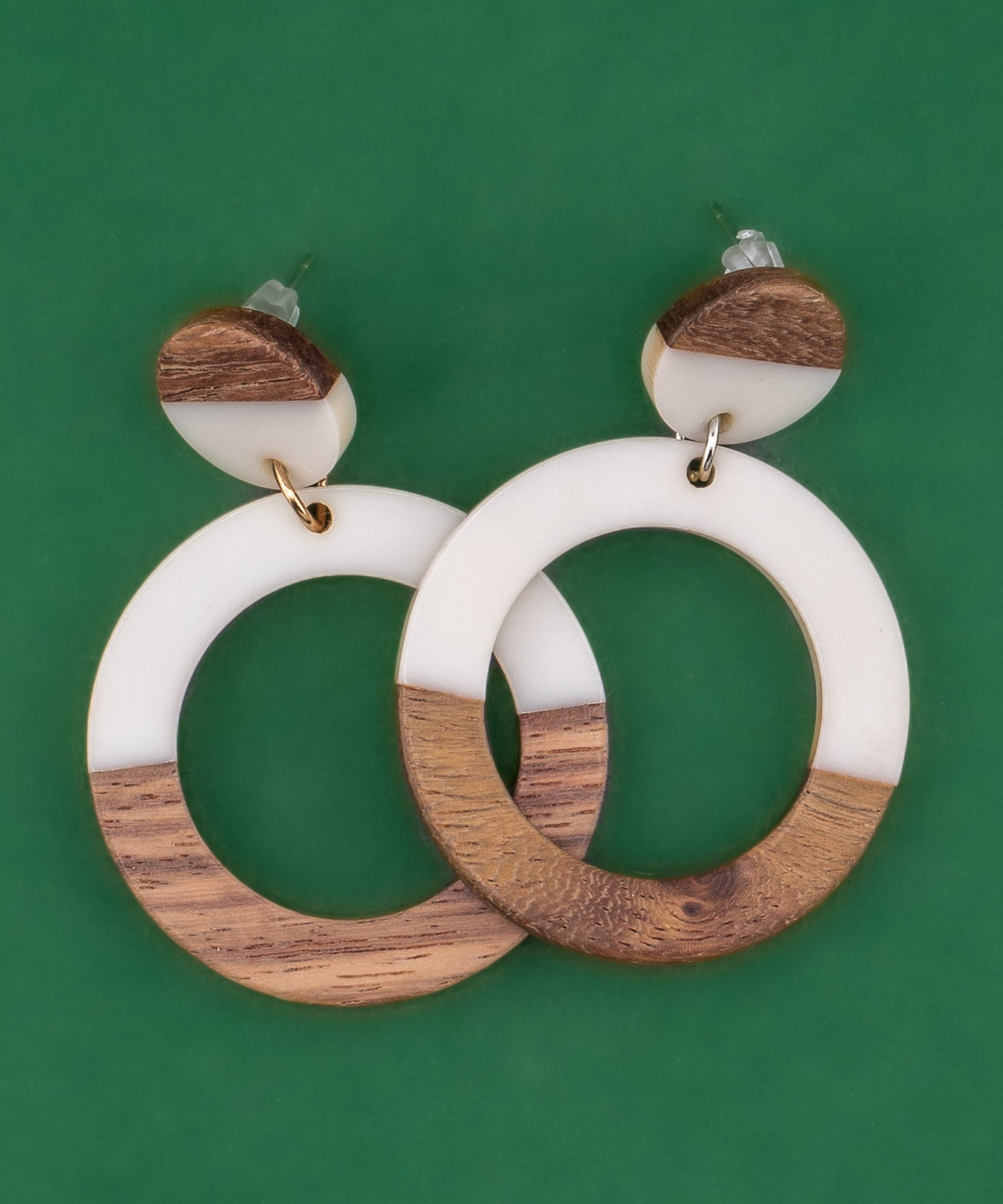 Wooden and white resin hoop earrings on a green background