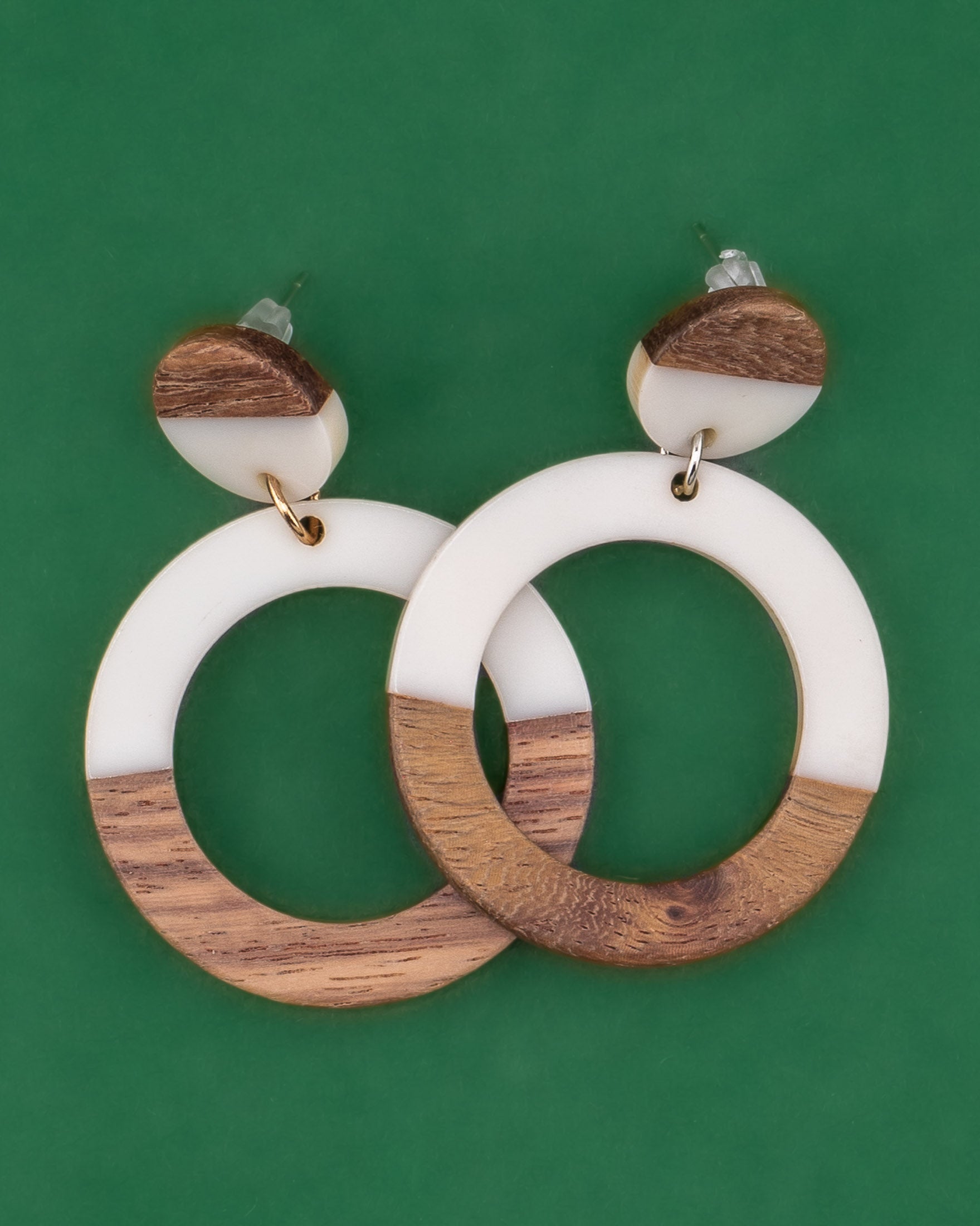 Wooden and white resin hoop earrings on a green background