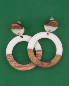 Wooden and white resin hoop earrings on a green background