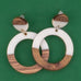 Wooden and white resin hoop earrings on a green background