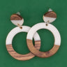 Wooden and white resin hoop earrings on a green background