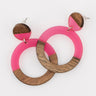 Pair of pink resin and wood circle earrings on a white background 