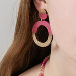 Close-up of a person wearing pink resin  and wood hoop earring by Kaleidoscope Living