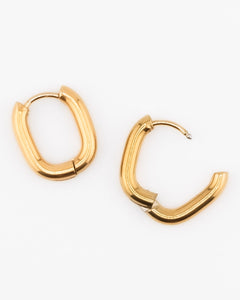 Gold oval hoop earrings on a white background